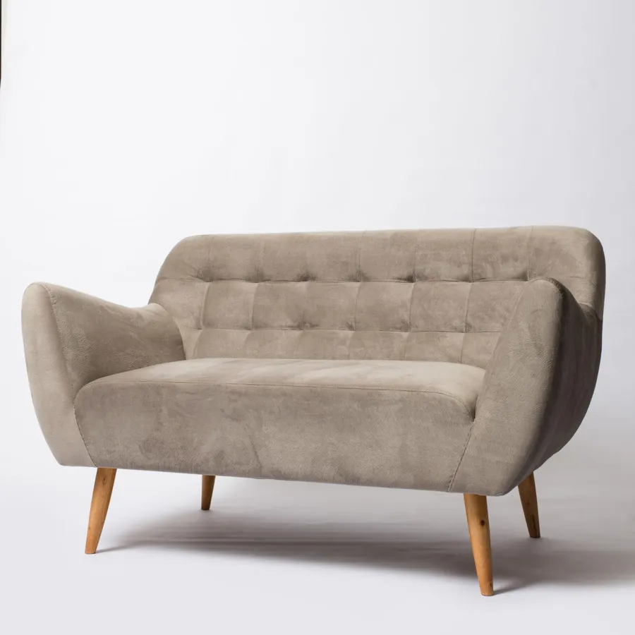 Plain studio photo of a beige two-seater tufted velvet sofa with wooden legs, before annotation