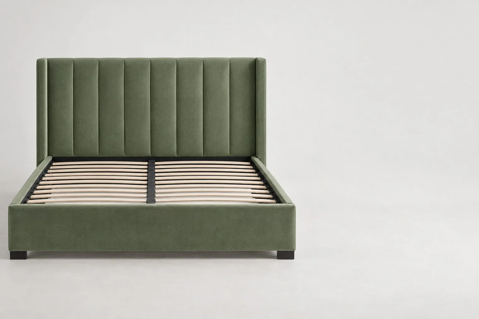 Green velvet upholstered bed frame with a channel-tufted wingback headboard and wooden slats, without annotations