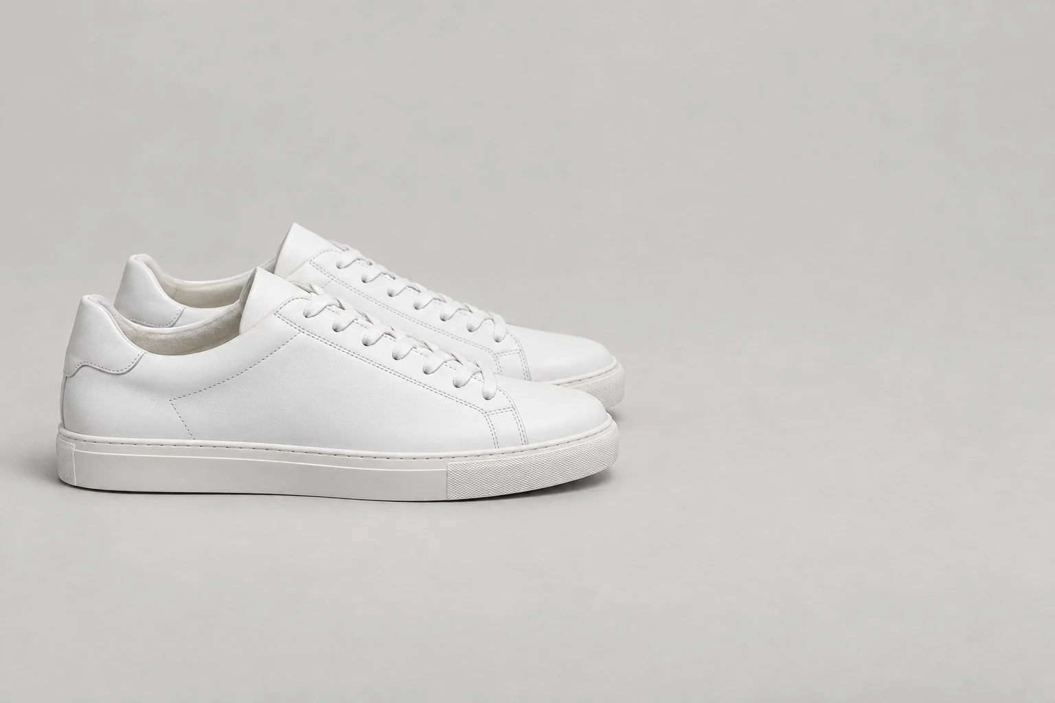 Pair of white leather low-top sneakers with white soles, without annotations